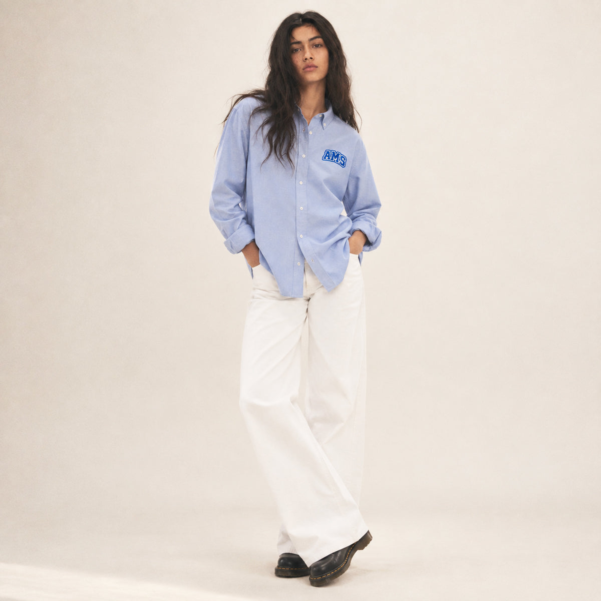 Chemise Oxford femme Beauséjour AMS bleu ciel en coton biologique, coupe élégante avec col classique, boutons blancs et patch AMS brodé sur la poitrine.