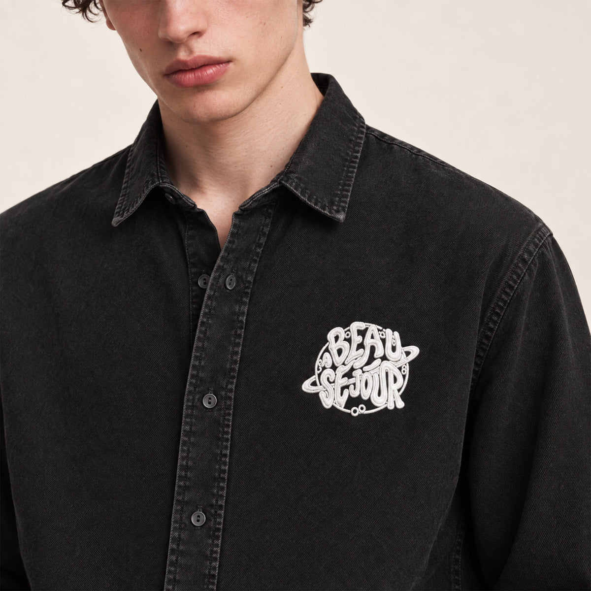 Chemise noire pour homme. Broderie planete sur le coeur. Vue de face. zoom broderie.
