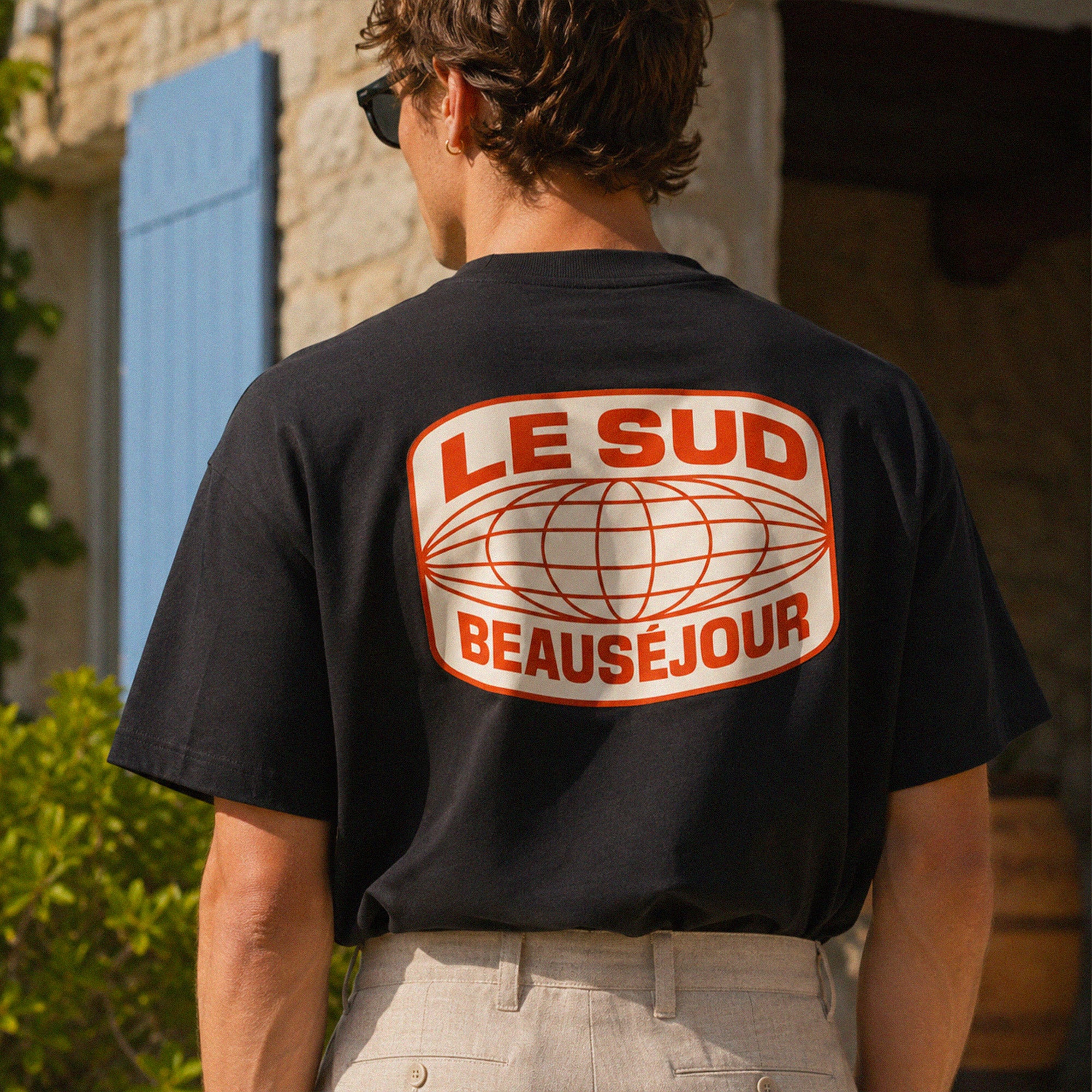 T-shirt oversize noir Beauséjour Le Sud en coton 200 grammes porté avec pantalon beige, coupe boxy et inspiration Côte d’Azur.