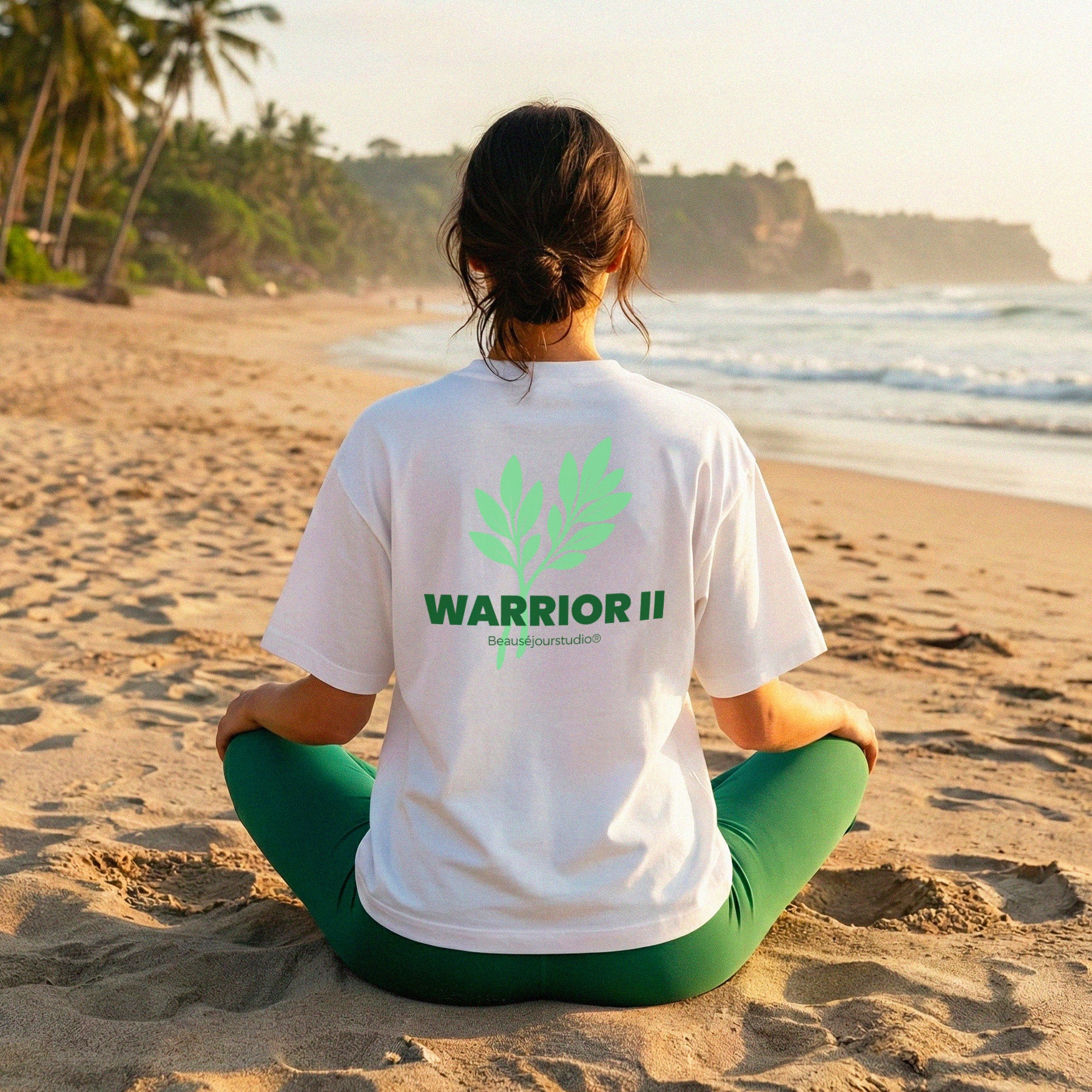 Femme a la plage de dos. Méditation. Elle porte le tshirt beausejour france Warrior II en coton 100% biologique. Parfait pour la pratique du yoga ou à porter tous les jours. T-Shirt Yoga pour femme - TShirt femme - TShirt pour femme - TShirt Lifestyle - pilate sport - yoga hatha - yoga cours - studio yoga - posture de yoga - yogastudio - yoga coaching