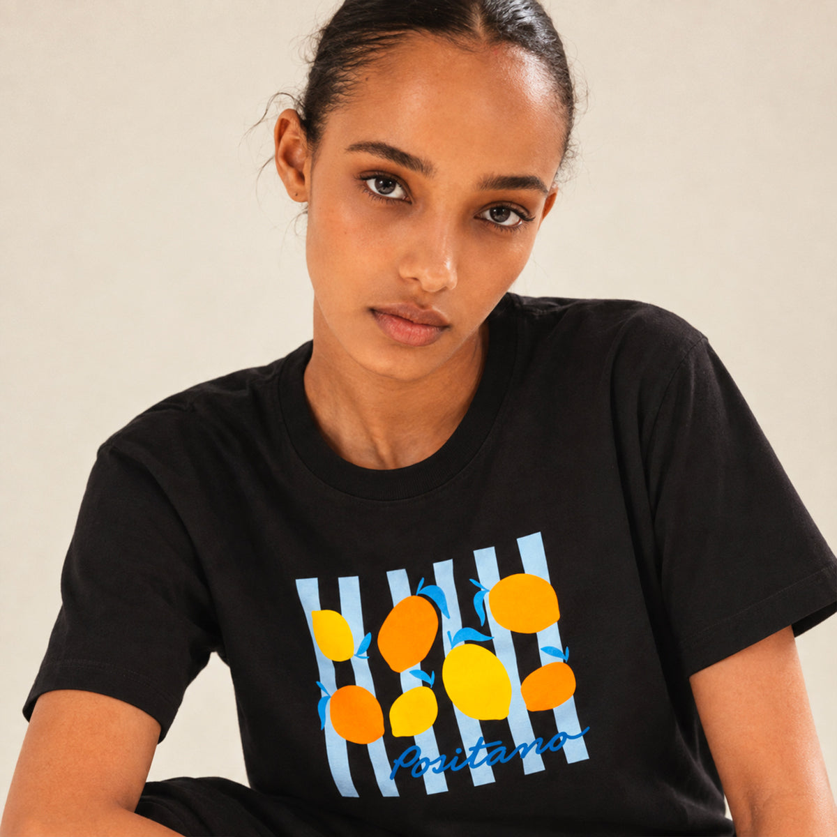 Femme portant un t-shirt noir Positano Beauséjour avec motif citron.
