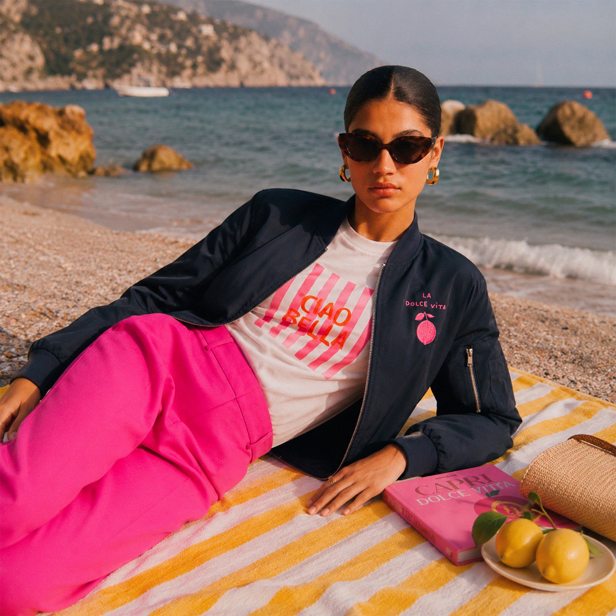 Look estival femme avec bomber marine et pantalon rose sur la cote italienne