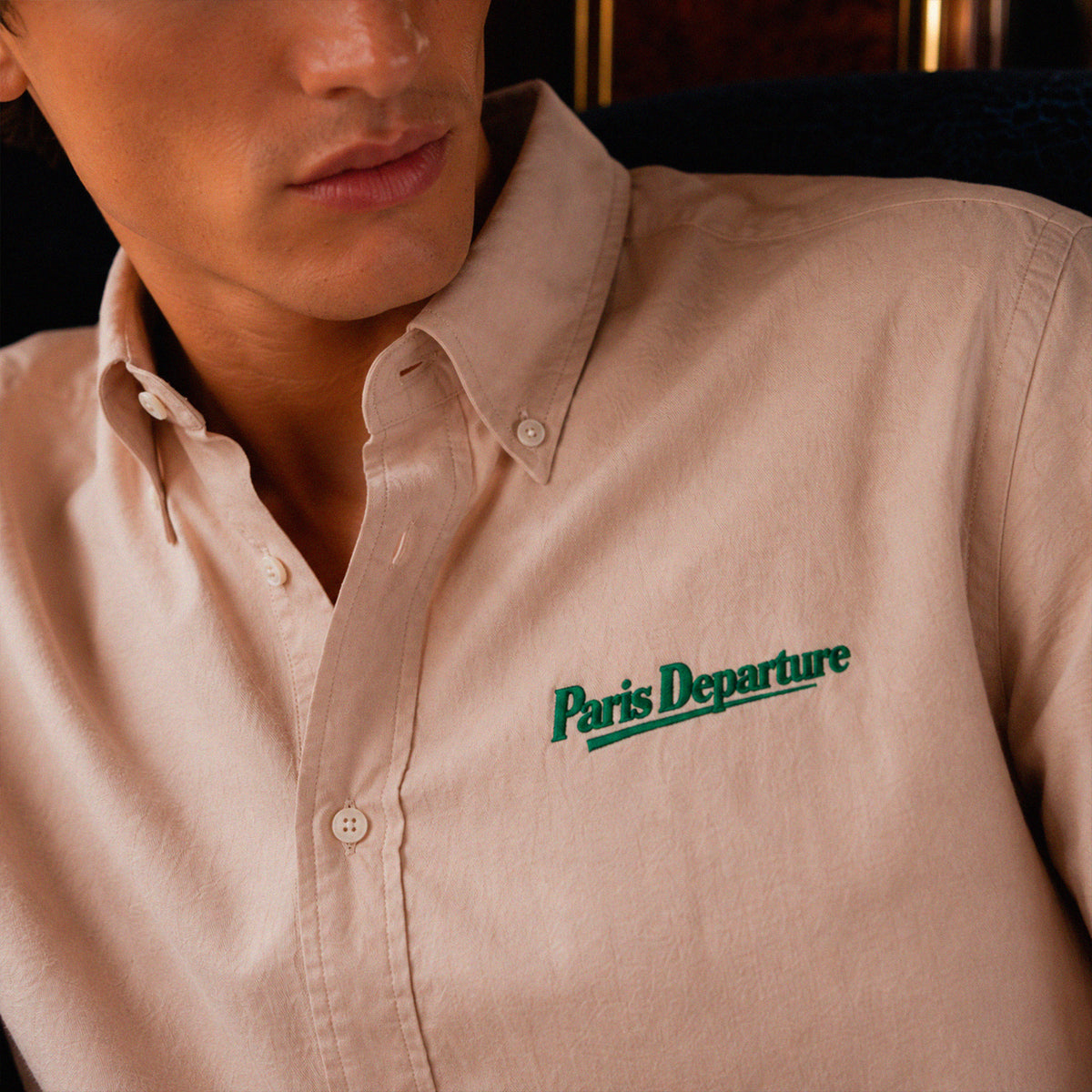 Chemise Oxford Paris Departure Beauséjour Orient Express, coloris crème, 100% coton biologique Oxford, broderie Paris Departure verte côté cœur inspirée des uniformes de voyage anciens, look complet.