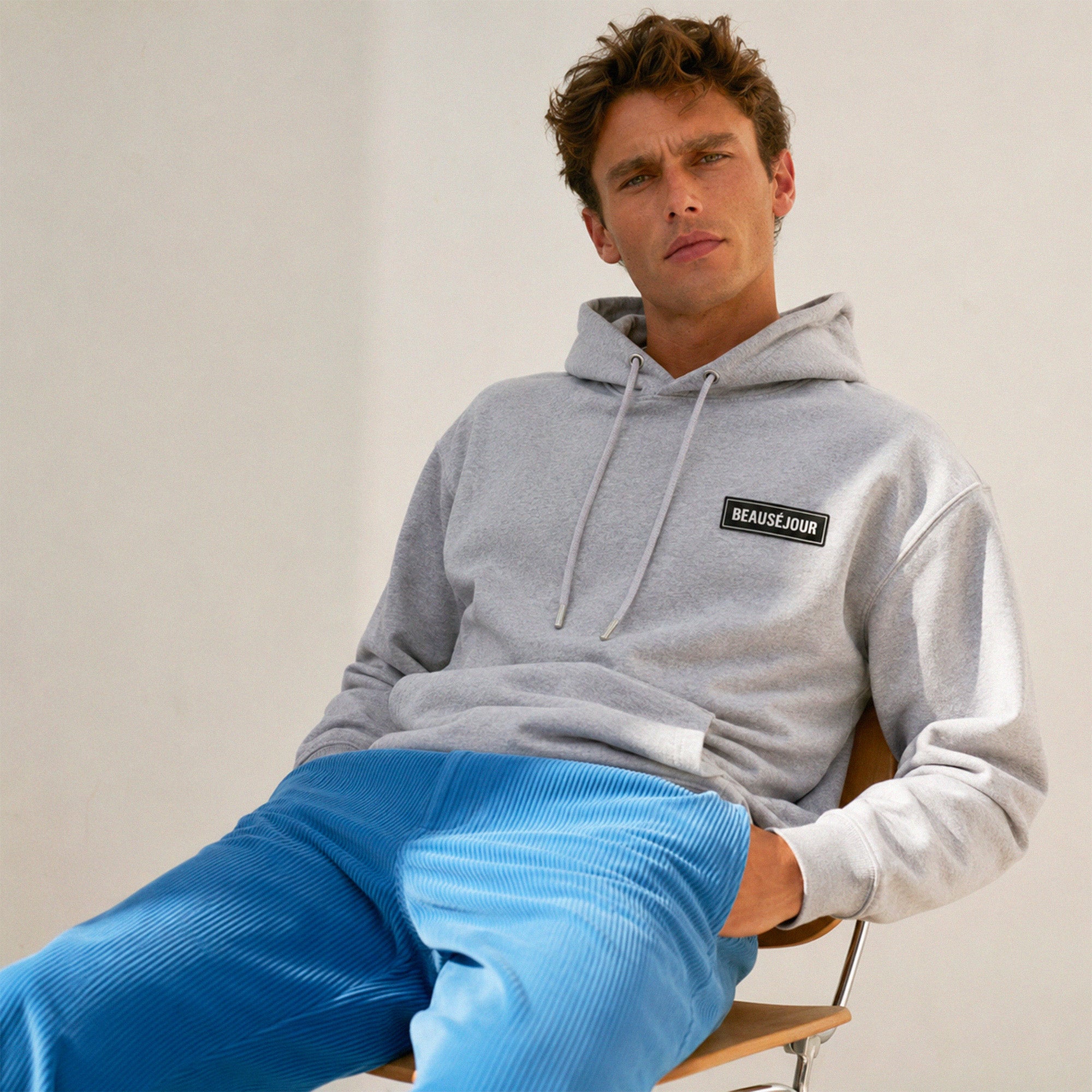 Hoodie basique Beauséjour® coloris gris, capuche et poches kangourou, coton épais 350g, patch Beauséjour noir sur blanc en poitrine, vue de face.