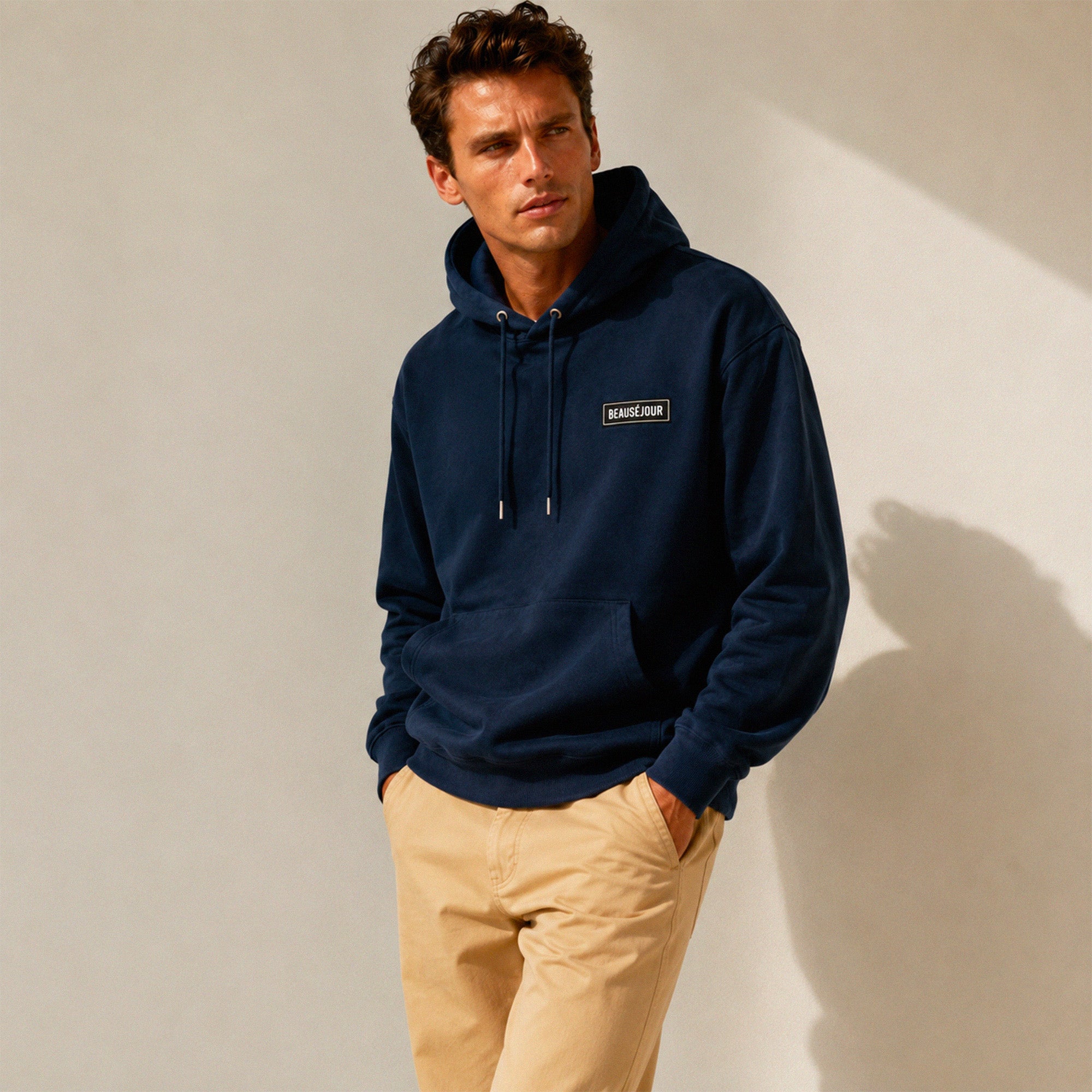 Hoodie basique Beauséjour® coloris marine, détail du patch Beauséjour noir sur blanc en poitrine et de la capuche.