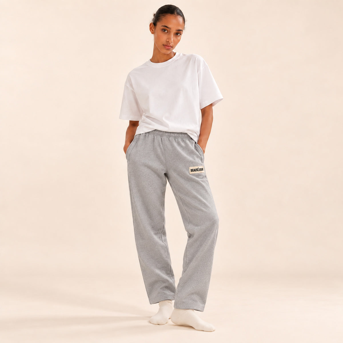Jogging gris femme Beauséjour, coupe droite et ample, taille élastique, poches latérales et patch brodé écru avec logo noir sur la cuisse.