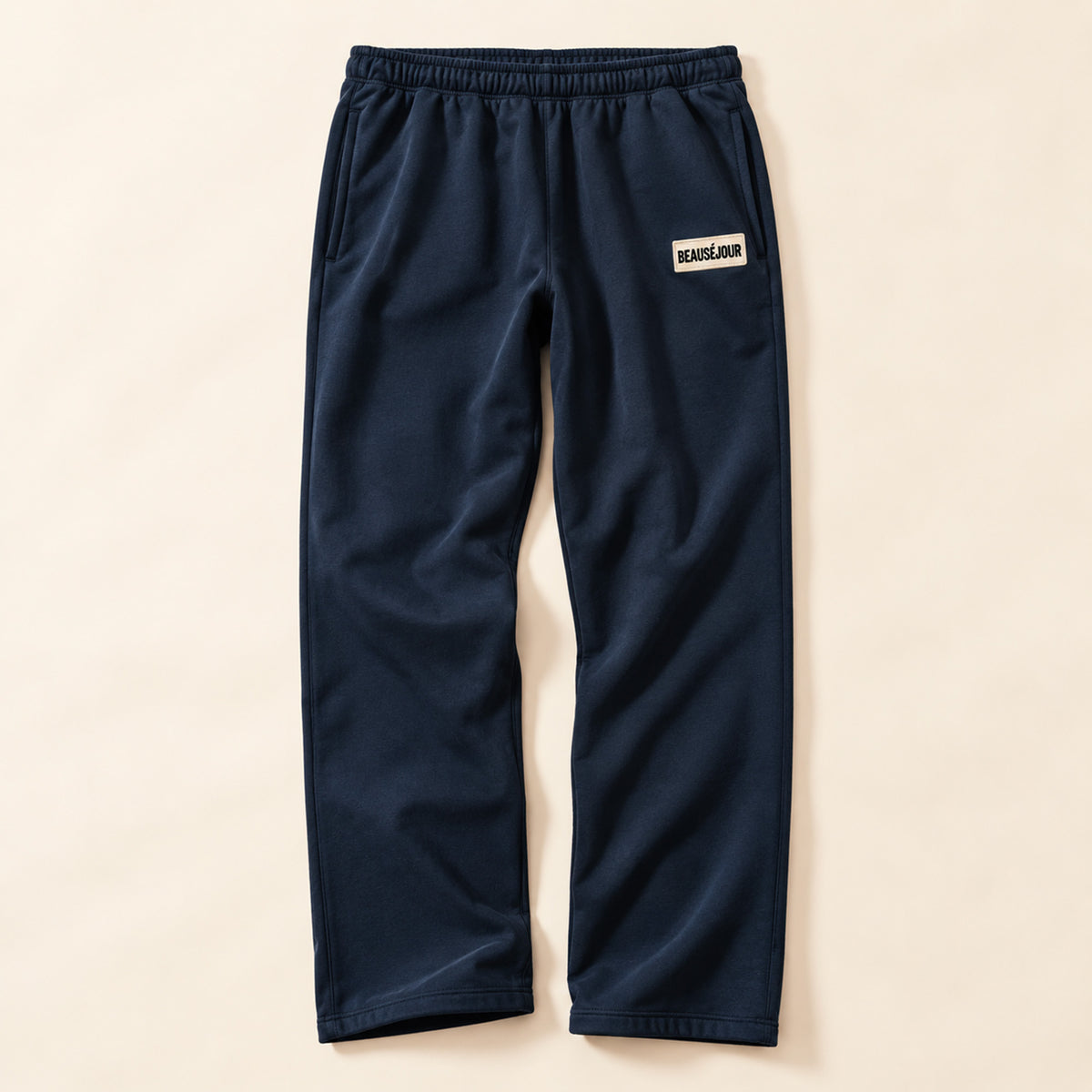 Jogging bleu marine femme Beauséjour, coupe droite et ample, taille élastique, poches latérales et patch brodé écru avec logo noir sur la cuisse.