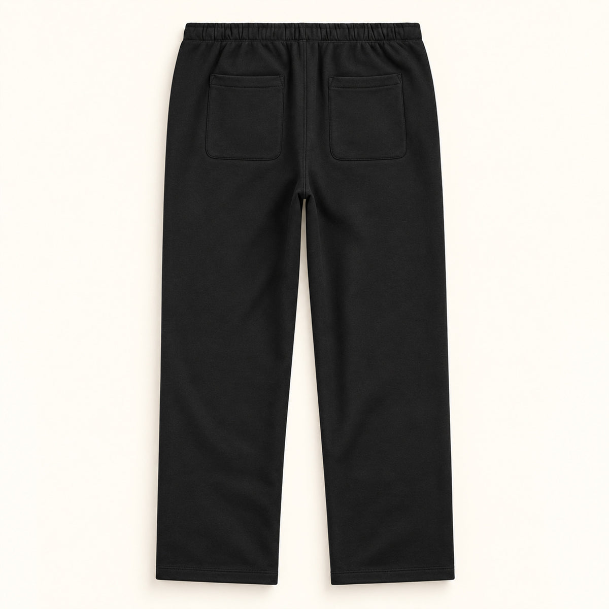 Jogging noir femme Beauséjour, coupe droite et ample, taille élastique, poches latérales et patch brodé écru avec logo noir sur la cuisse. Vue de dos.