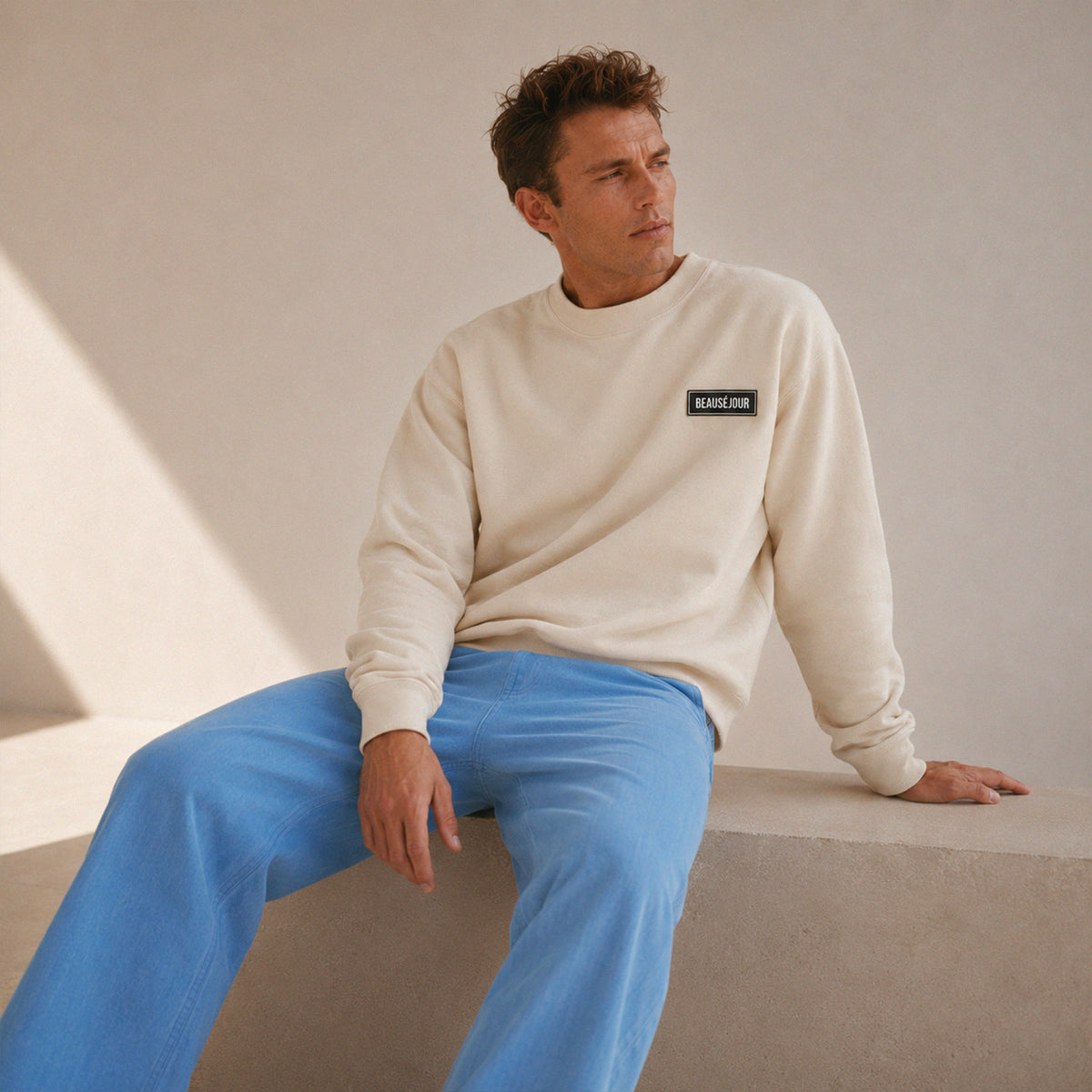 Sweatshirt basique Beauséjour® col rond coloris crème, détail du patch Beauséjour noir sur blanc et de la surpiqûre à l'encolure.