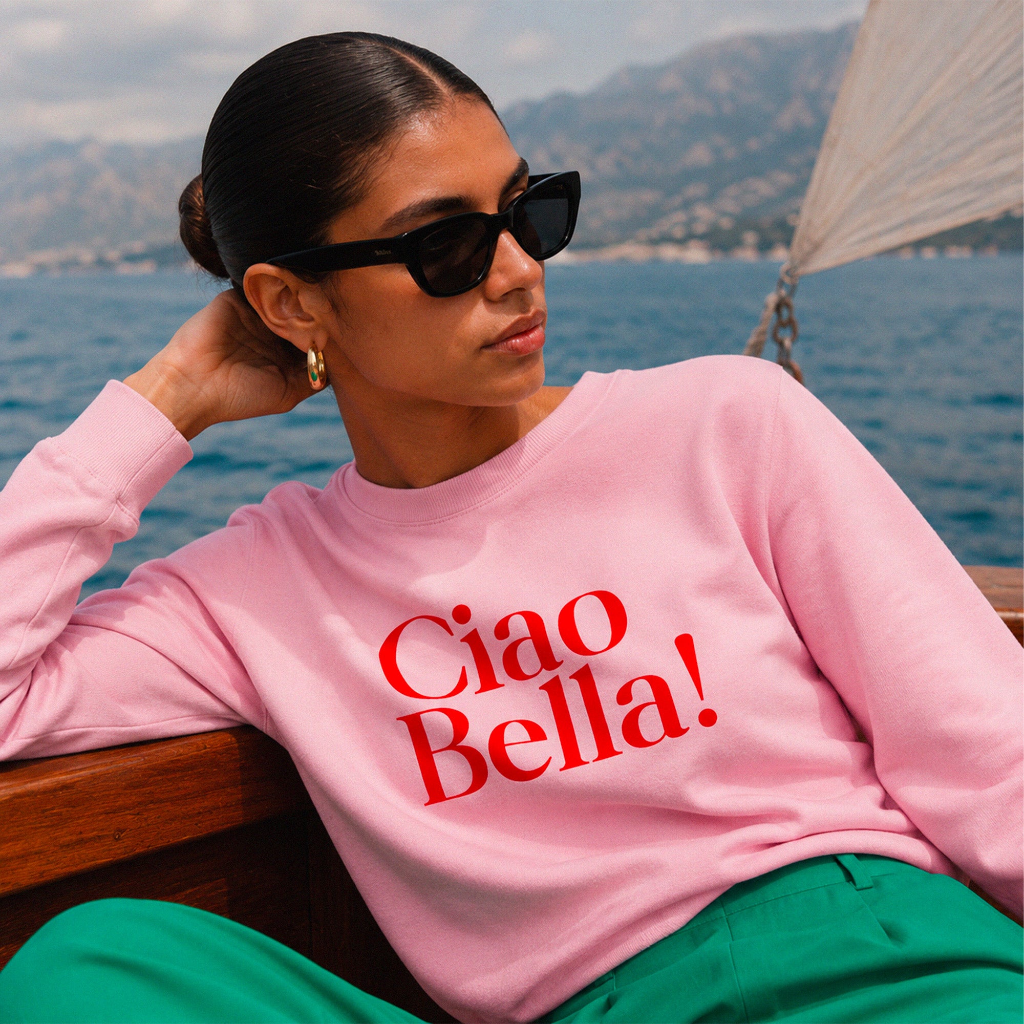 Femme portant un sweatshirt rose Ciao Bella sur un bateau en Mediterranee