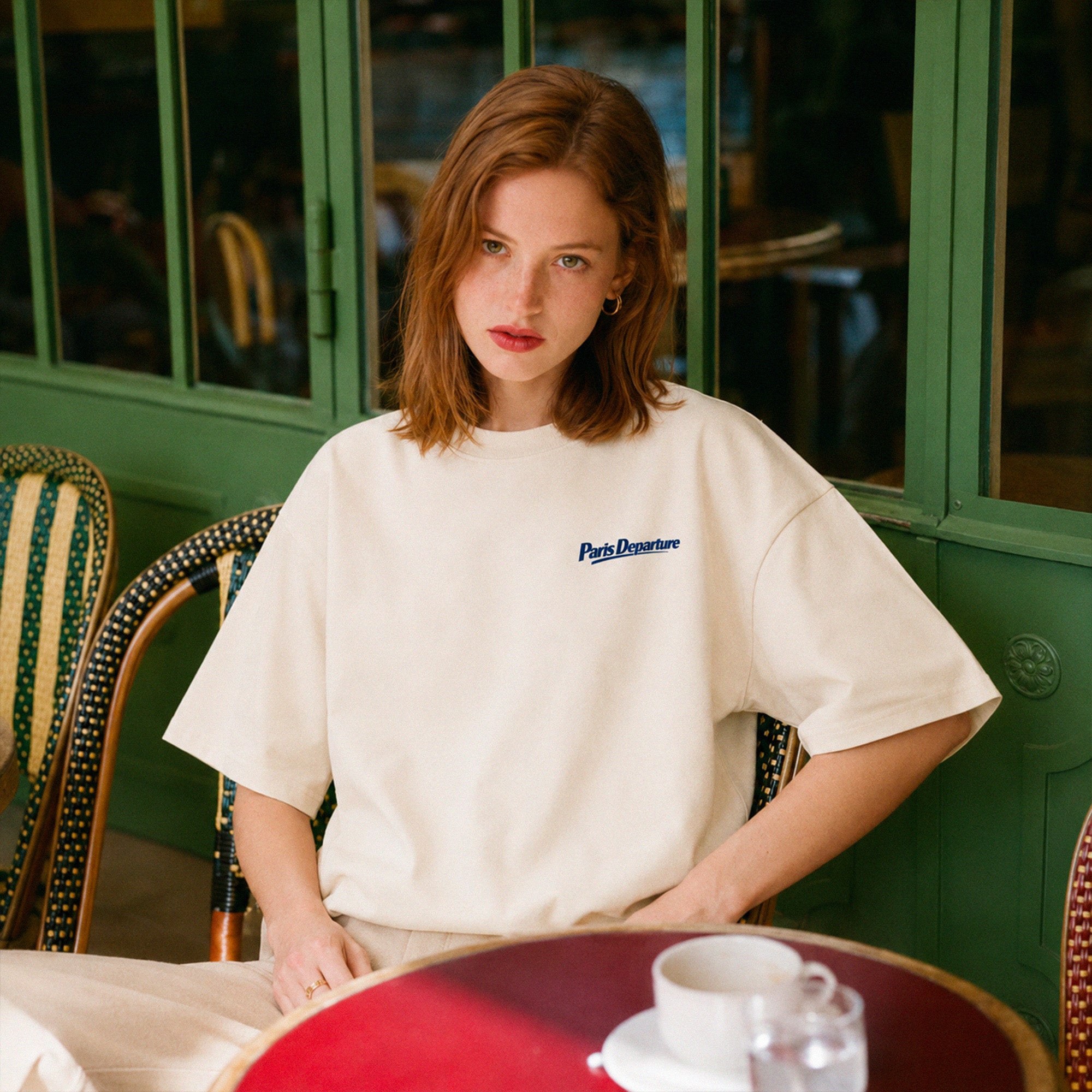 T-shirt boxy Paris Departure Beauséjour Orient Express, coloris crème, jersey 200 g/m² 100% coton biologique, imprimé Paris Departure côté cœur et logo dos façon billet de train, vue de face.