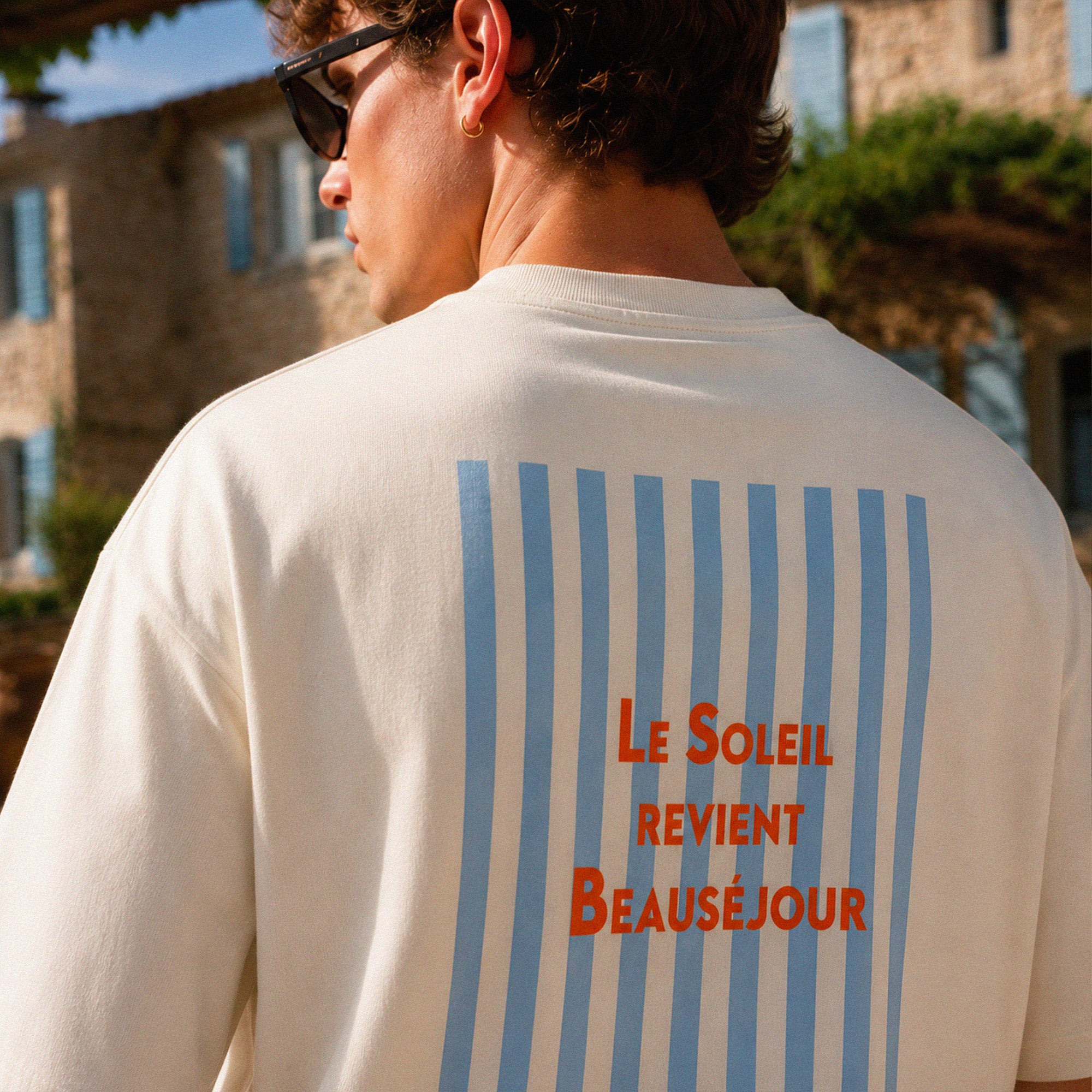 Homme portant le t-shirt oversize crème Beauséjour Le Soleil Revient en coton 200 grammes, style vacances Côte d’Azur.