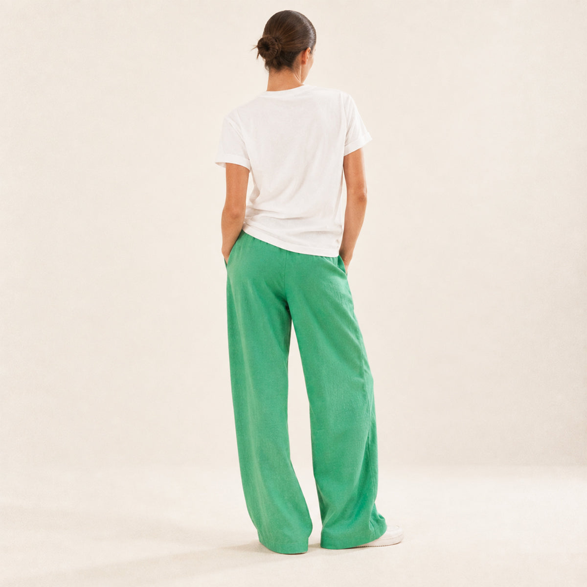 Femme portant un t-shirt blanc Ciao Bella vert Beauséjour avec lettrage vert. Vue de dos.