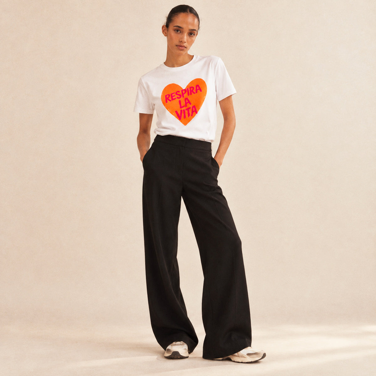 Femme portant un t-shirt blanc Respira la Vita Beauséjour, imprimé orange.