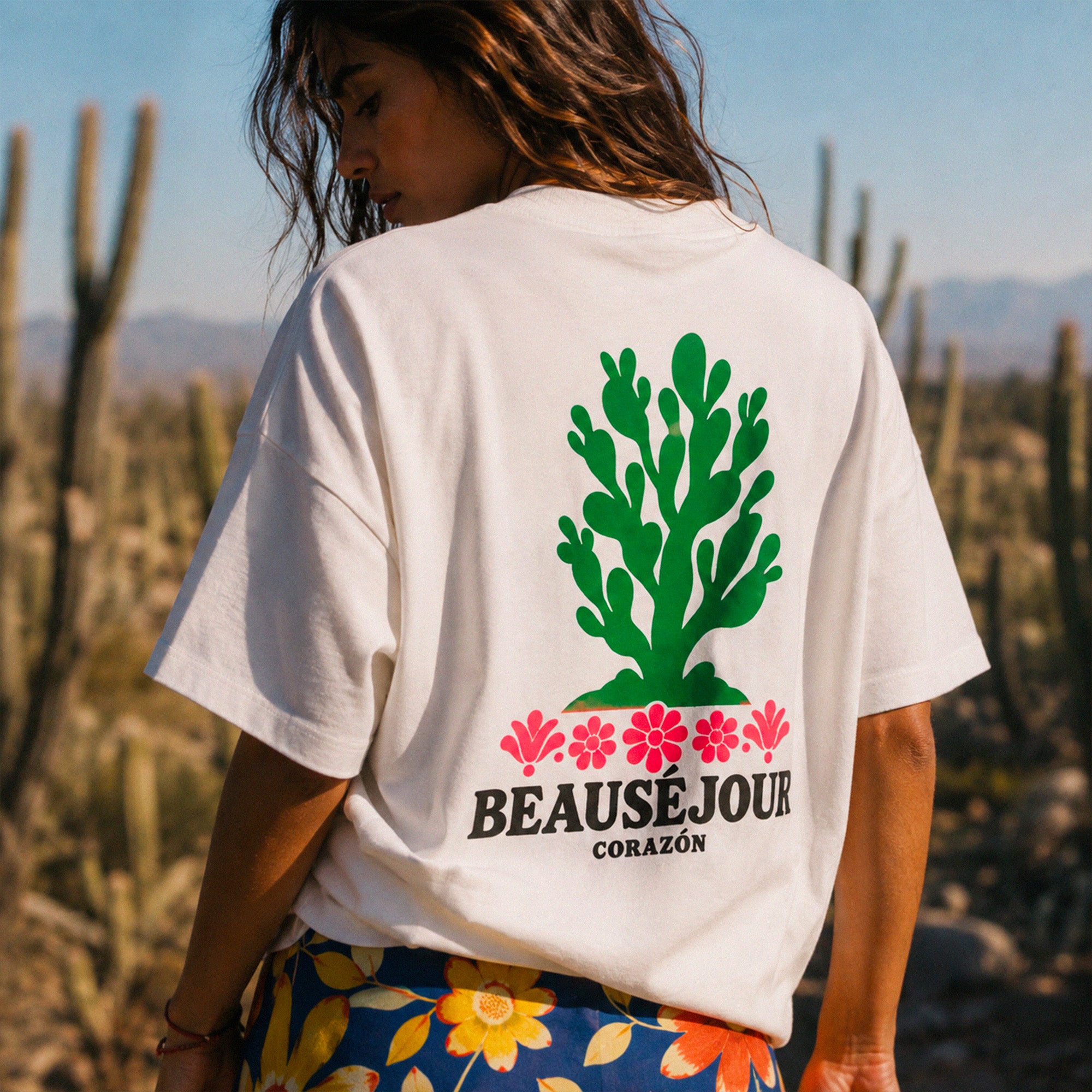 T-shirt boxy blanc Beauséjour Corazón en coton biologique, avec illustration cactus verte et fleurs roses inspirée du Mexique, petit logo poitrine et grand imprimé dans le dos.