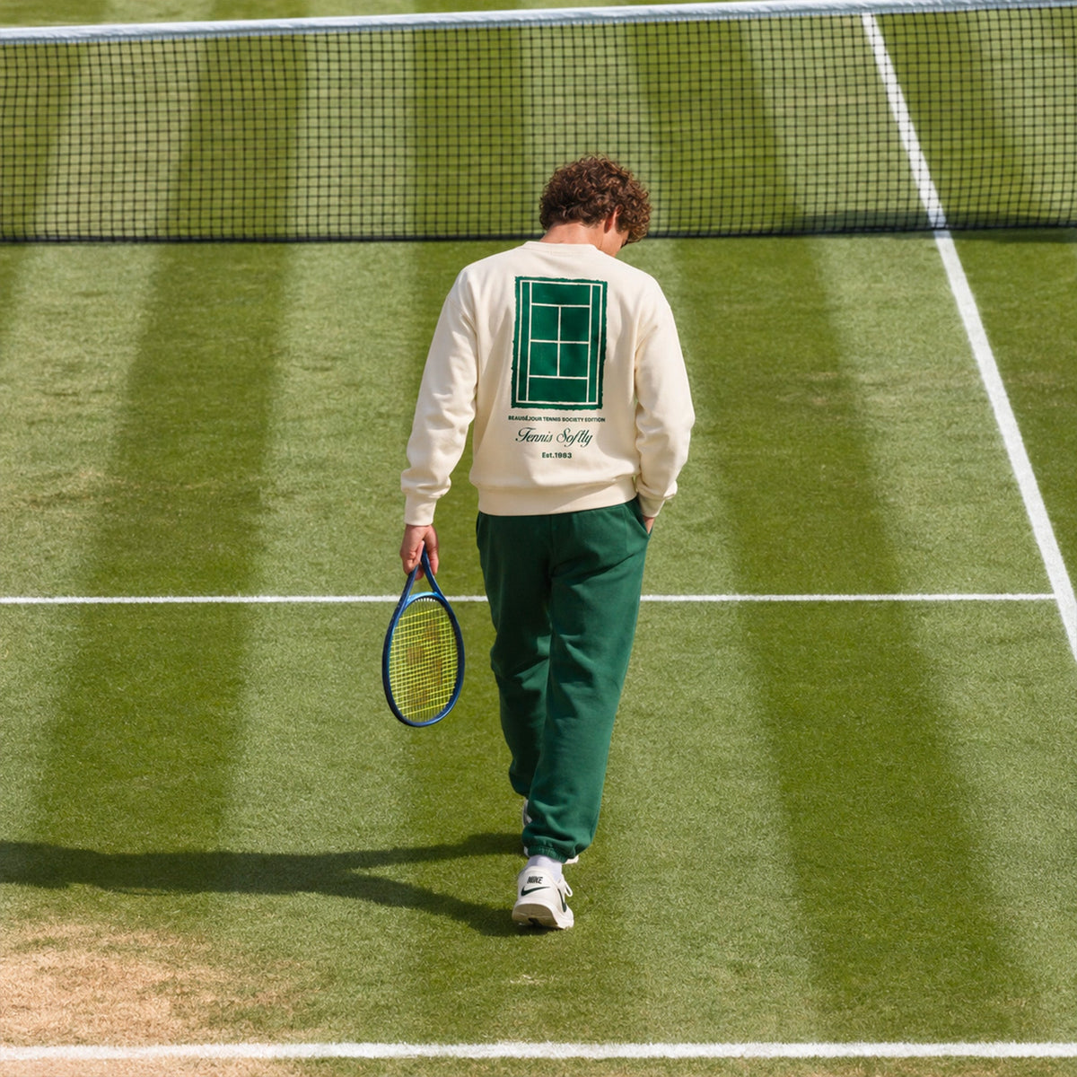 Joueur de dos sur un court en gazon, sweatshirt tennis crème Beauséjour