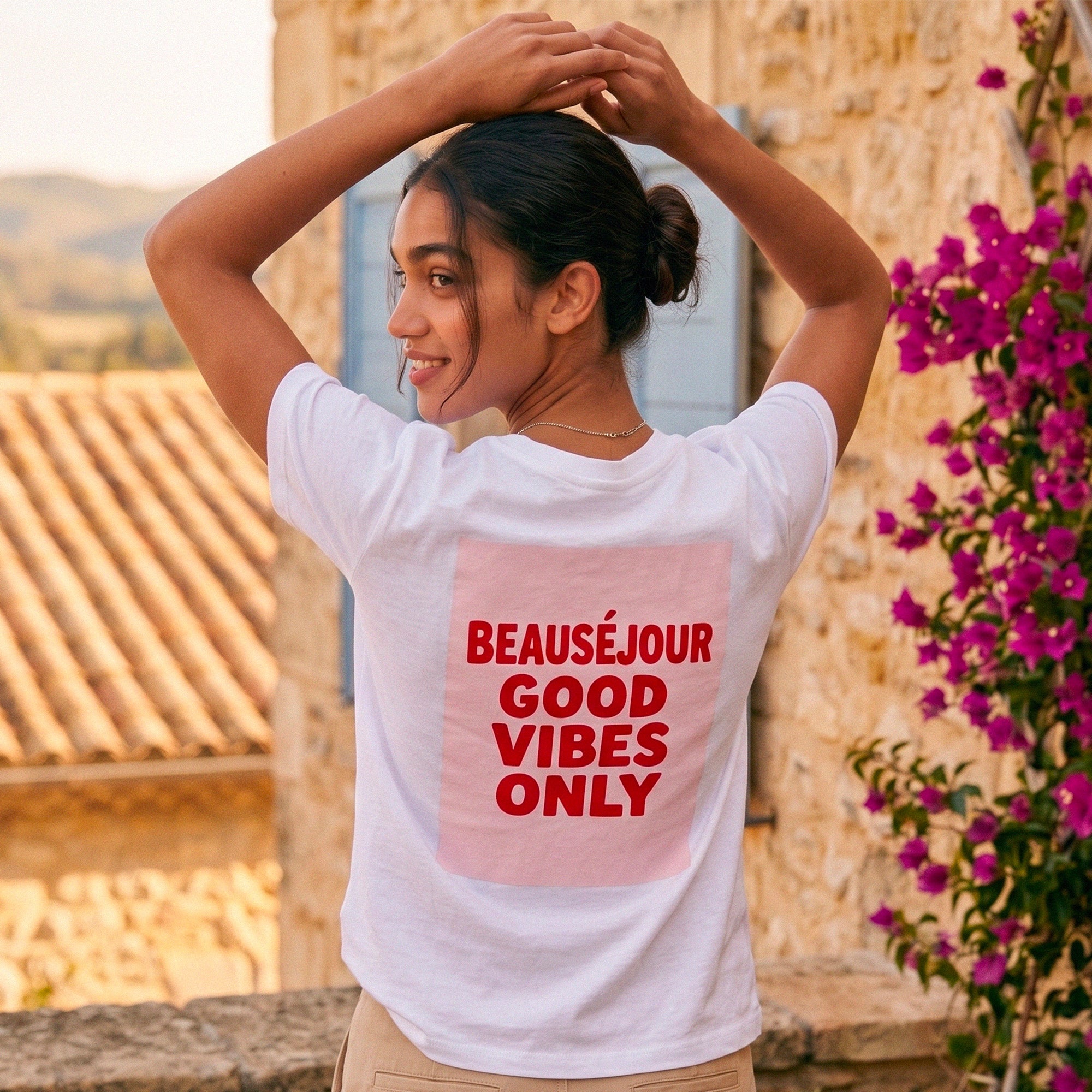 T-shirt blanc femme Beauséjour "Good Vibes Only", imprimé rouge au dos, style été dolce vita, coupe casual chic, porté en extérieur en décor méditerranéen.