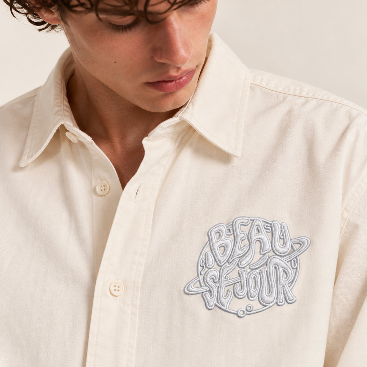 Chemise creme pour homme. Broderie planete sur le coeur. Vue de face. zoom broderie.