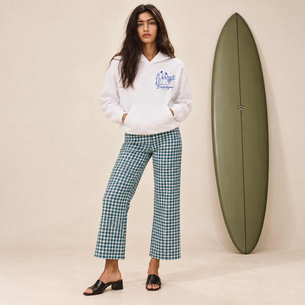 Hoodie Biarritz after surf blanc porté par une femme à côté d'une planche de surf