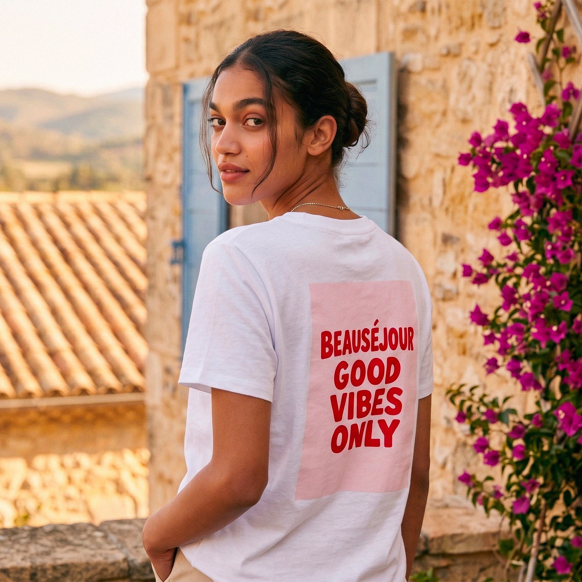 T-shirt blanc femme Beauséjour "Good Vibes Only", imprimé rouge au dos, style été dolce vita, coupe casual chic, porté en extérieur en décor méditerranéen.
