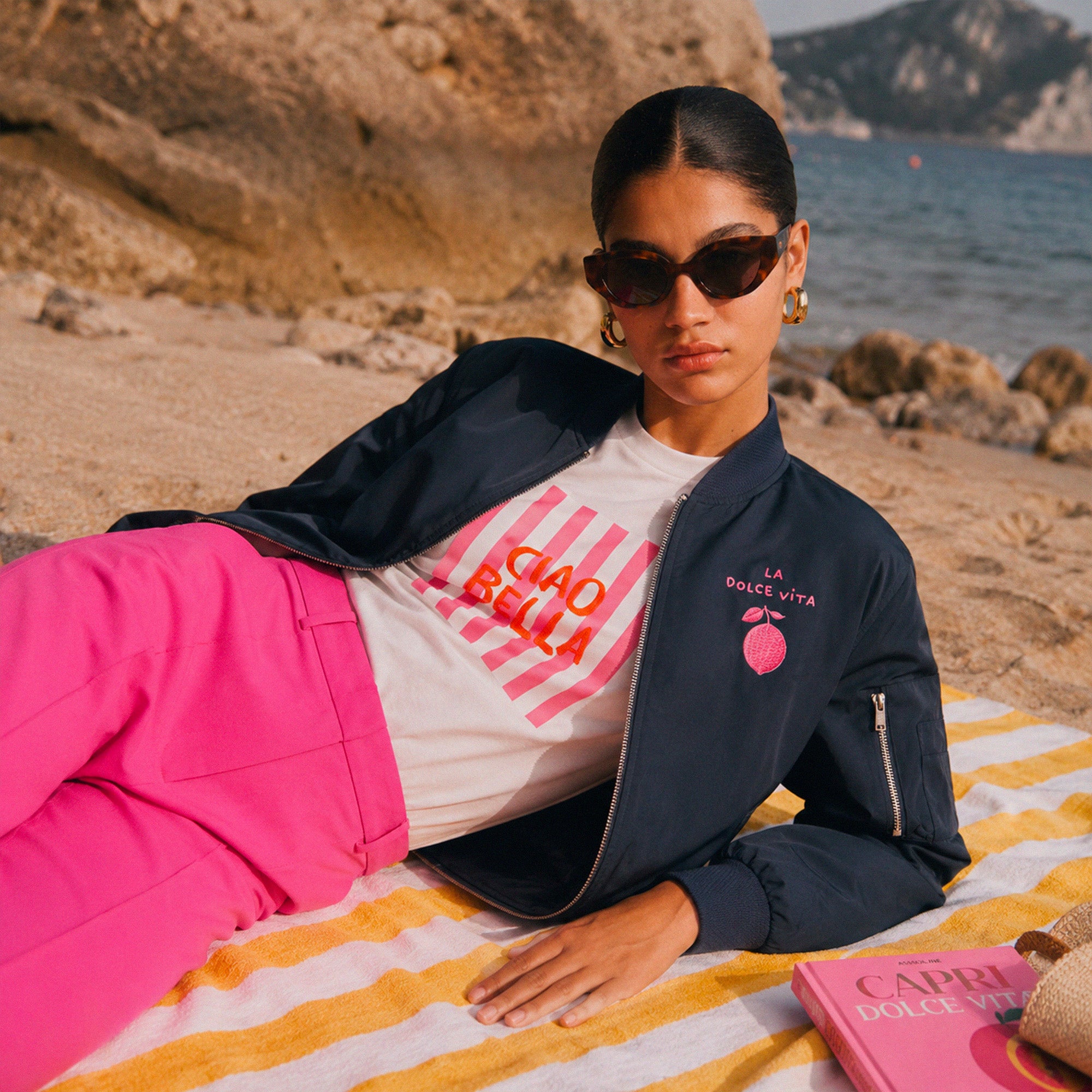 Femme portant un bomber noir Dolce Vita citron sur une plage mediterraneenne