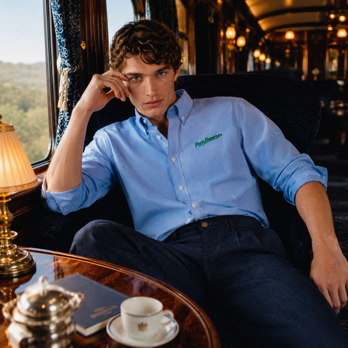 Chemise Oxford Paris Departure Beauséjour Orient Express, coloris bleu Oxford, 100% coton biologique Oxford, broderie Paris Departure verte côté cœur inspirée des uniformes de voyage anciens, vue de dos.