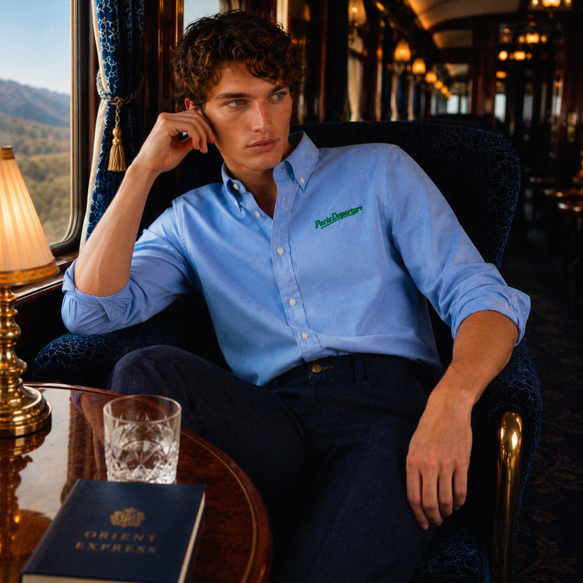 Chemise Oxford Paris Departure Beauséjour Orient Express, coloris bleu Oxford, 100% coton biologique Oxford, broderie Paris Departure verte côté cœur inspirée des uniformes de voyage anciens, look complet.