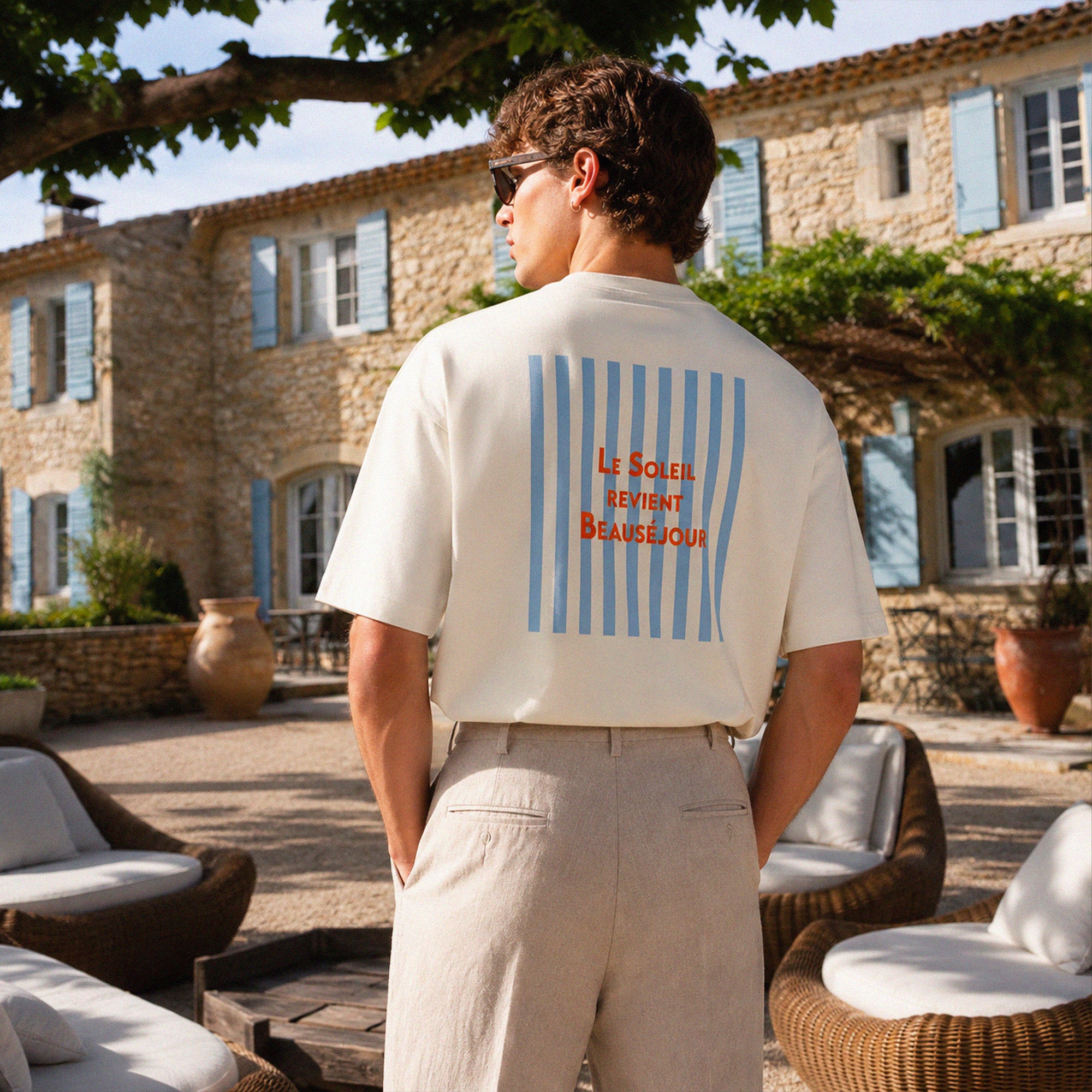 Détail du dos du t-shirt Le Soleil Revient Beauséjour avec graphisme vintage bleu ciel et rouge inspiré des parasols d’été.