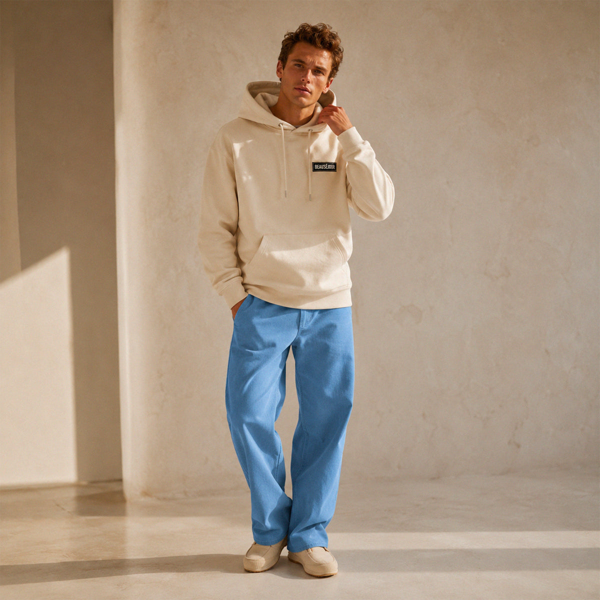 Hoodie basique Beauséjour® coloris crème, détail du patch Beauséjour noir sur blanc en poitrine et de la capuche.