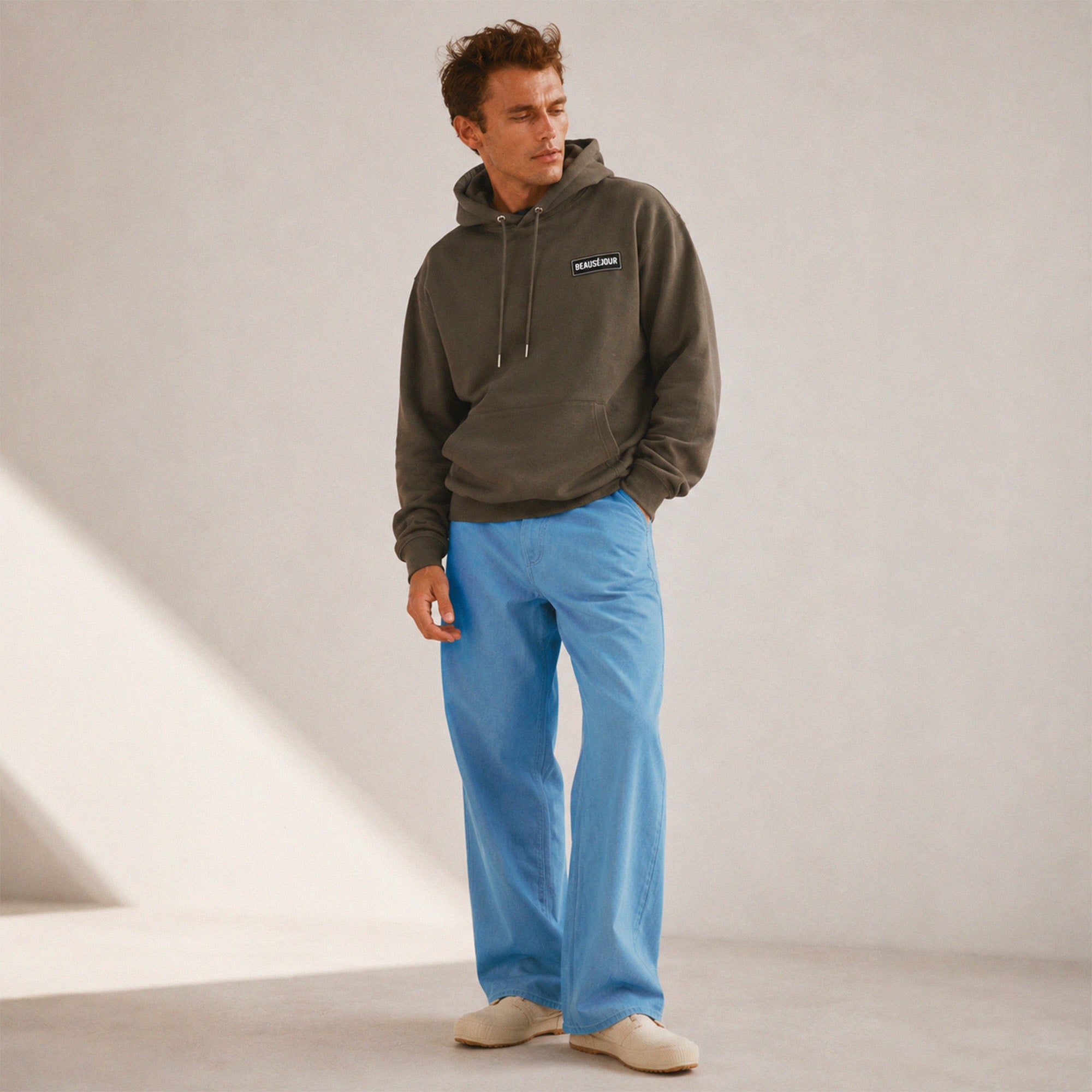 Hoodie basique Beauséjour® coloris kaki, détail du patch Beauséjour noir sur blanc en poitrine et de la capuche.
