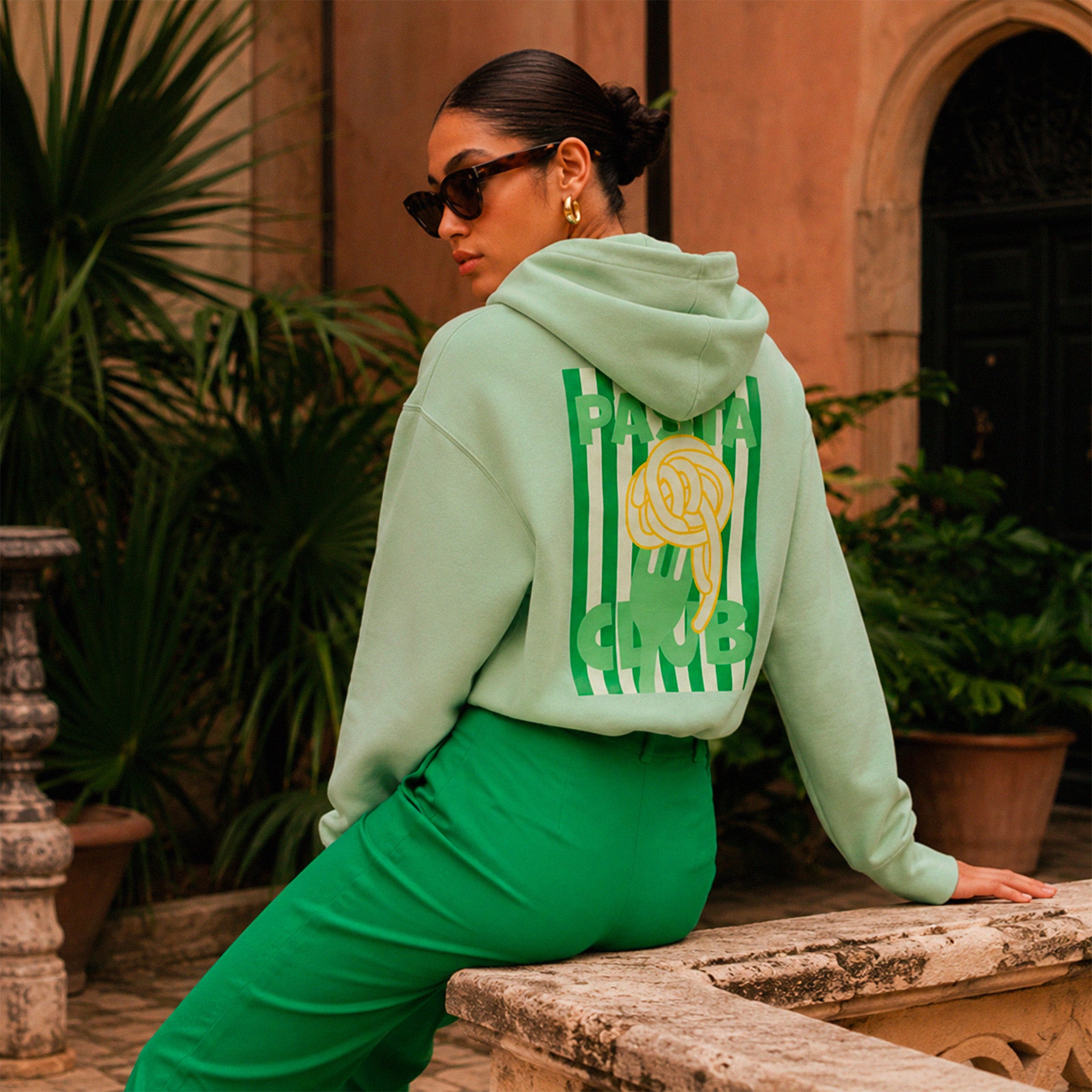Femme portant un hoodie Pasta Club aloe avec illustration italienne