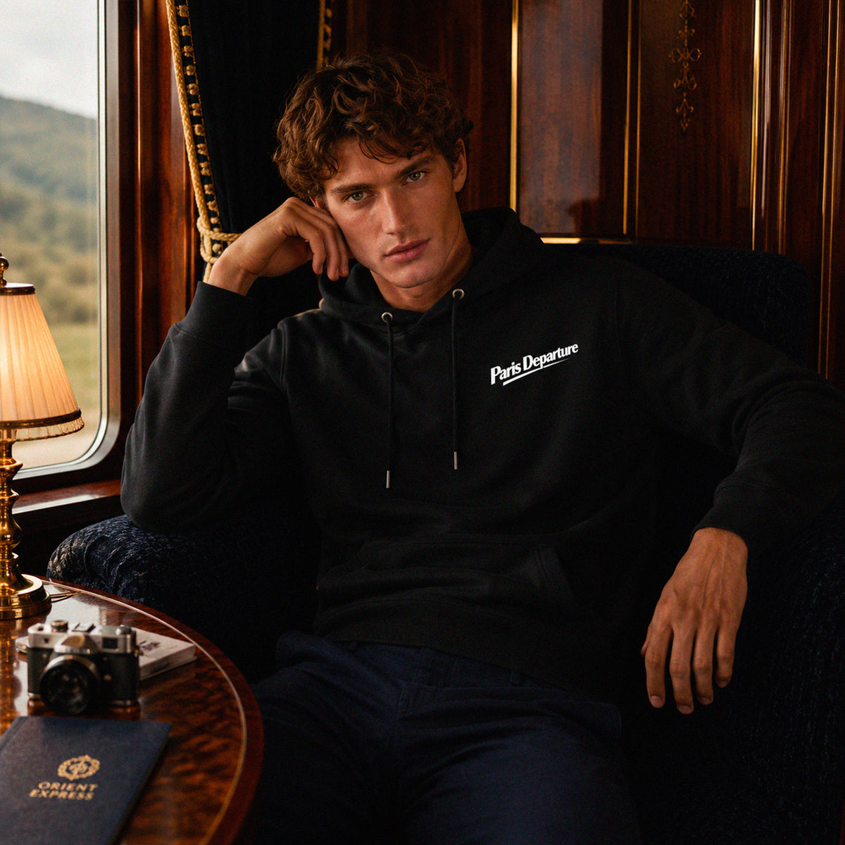 Hoodie Paris Departure Beauséjour Orient Express, coloris noir profond, 100% coton biologique molleton brossé, imprimé Paris Departure côté cœur et marquage dos inspiré des compagnies de voyage anciennes, vue de face.