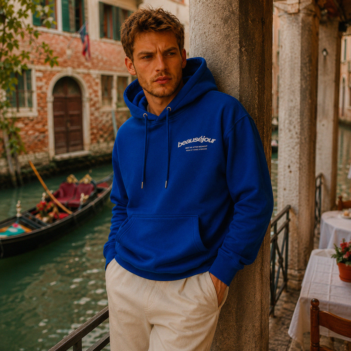 Hoodie Room 27 Venice Beauséjour Orient Express, coloris bleu royal, logo poitrine minimaliste et grand imprimé dos "Beauséjour — Meet Me After Midnight — Room 27 Venice Stopover", capuche ajustable et poche kangourou, vue de dos.