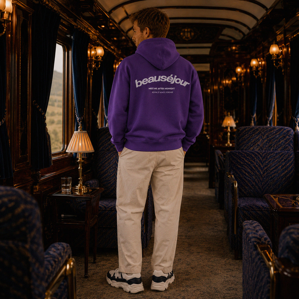 Hoodie Room 27 Venice Beauséjour Orient Express, coloris violet profond, logo poitrine minimaliste et grand imprimé dos "Beauséjour — Meet Me After Midnight — Room 27 Venice Stopover", capuche ajustable et poche kangourou, vue de dos.