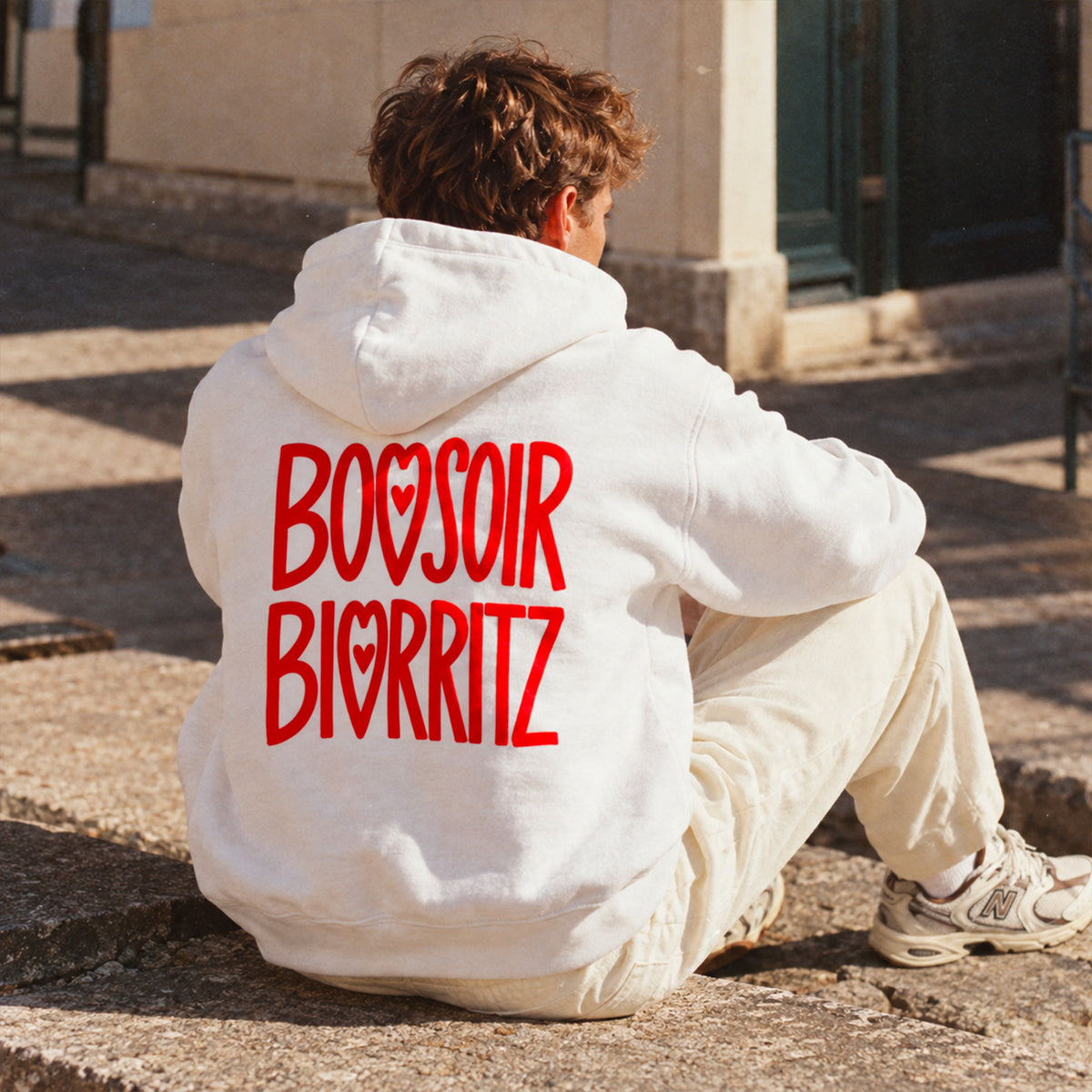 homme portant un hoodie blanc bonsoir biarritz. vue de dos.