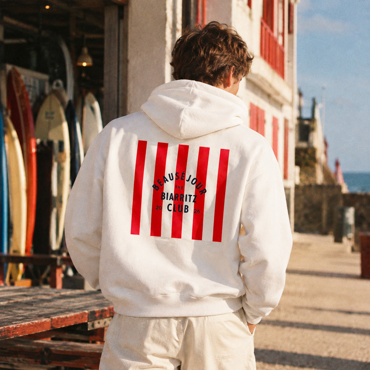 Hoodie Biarritz Club blanc, homme en bord de plage.