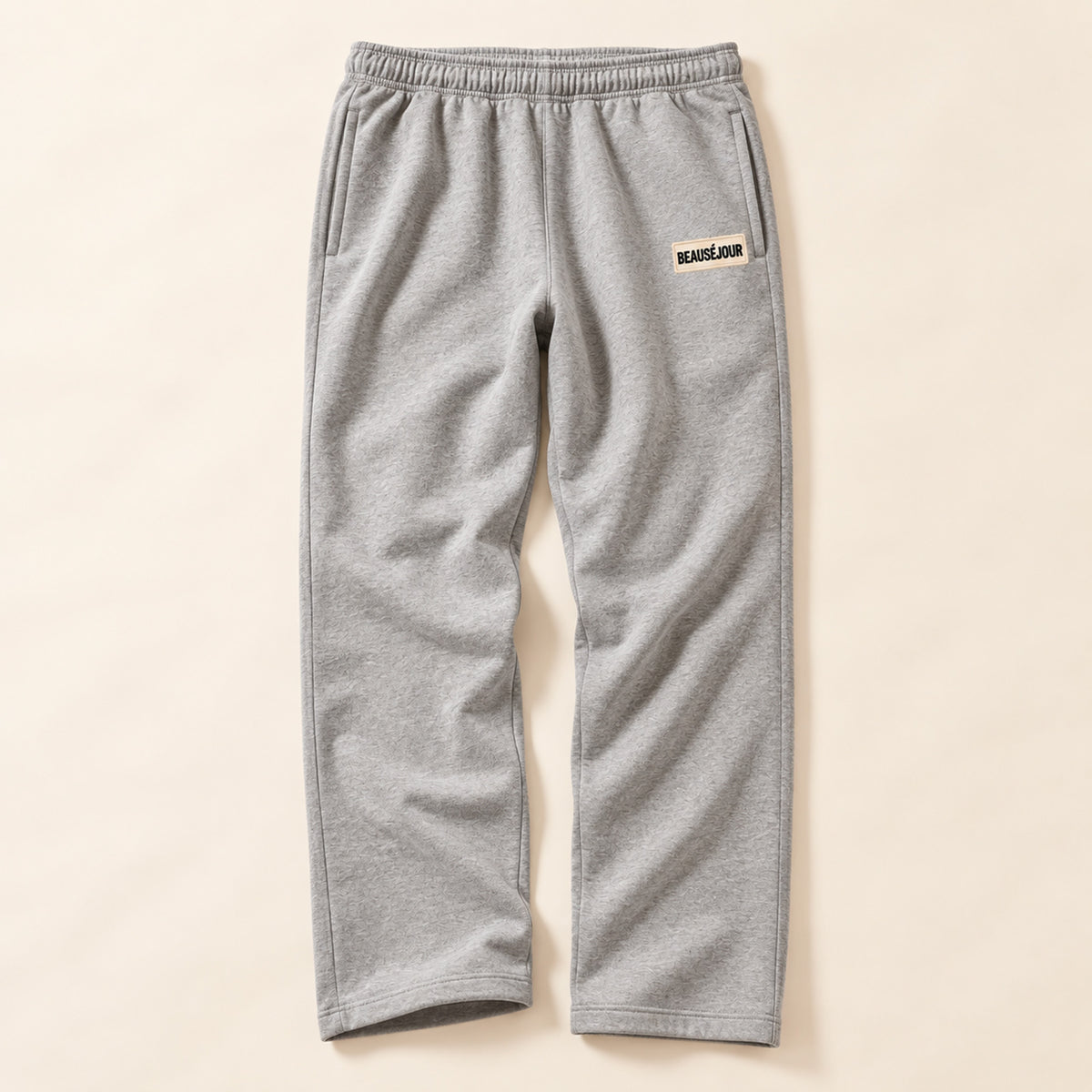 Jogging gris femme Beauséjour, coupe droite et ample, taille élastique, poches latérales et patch brodé écru avec logo noir sur la cuisse.