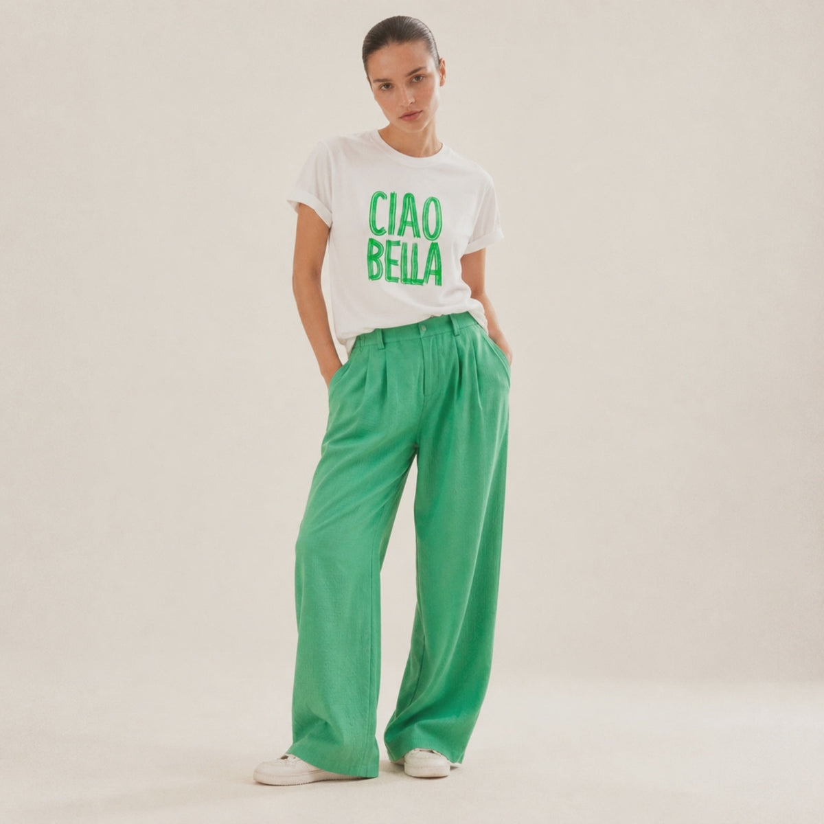 Film Femme portant un t-shirt blanc Ciao Bella vert Beauséjour avec lettrage vert.
