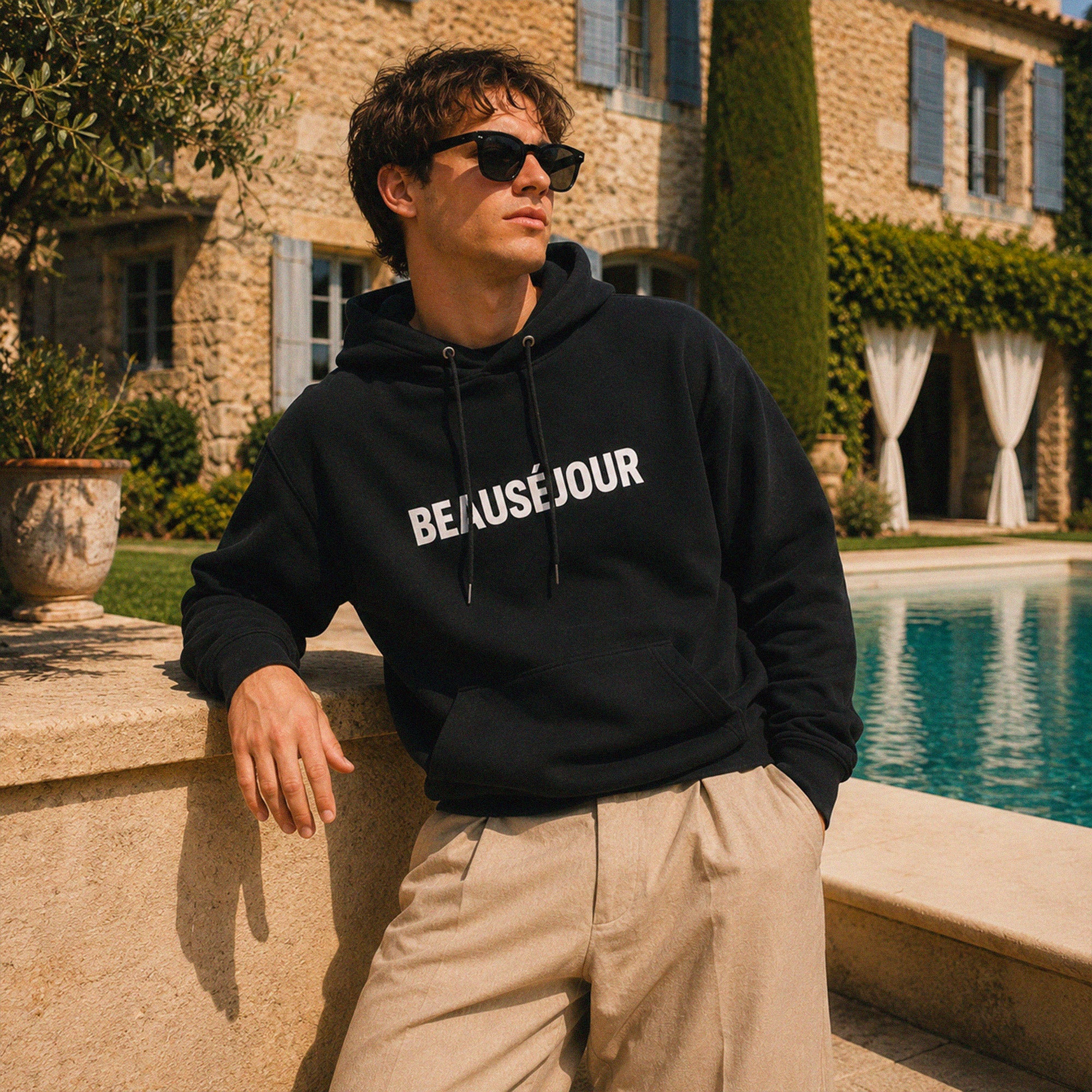 Sweat hoodie Beauséjour noir porté au soleil avec inspiration vacances, plage et élégance méditerranéenne.