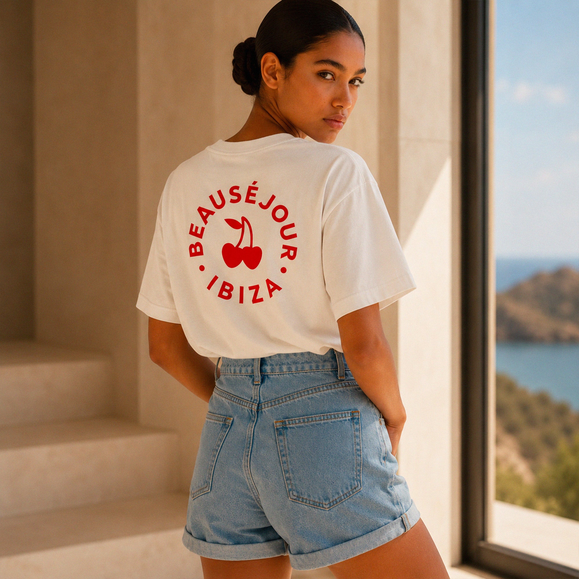 Femme portant un tshirt blanc Beausejour Ibiza cercle avec logo rouge dans une villa mediterraneenne