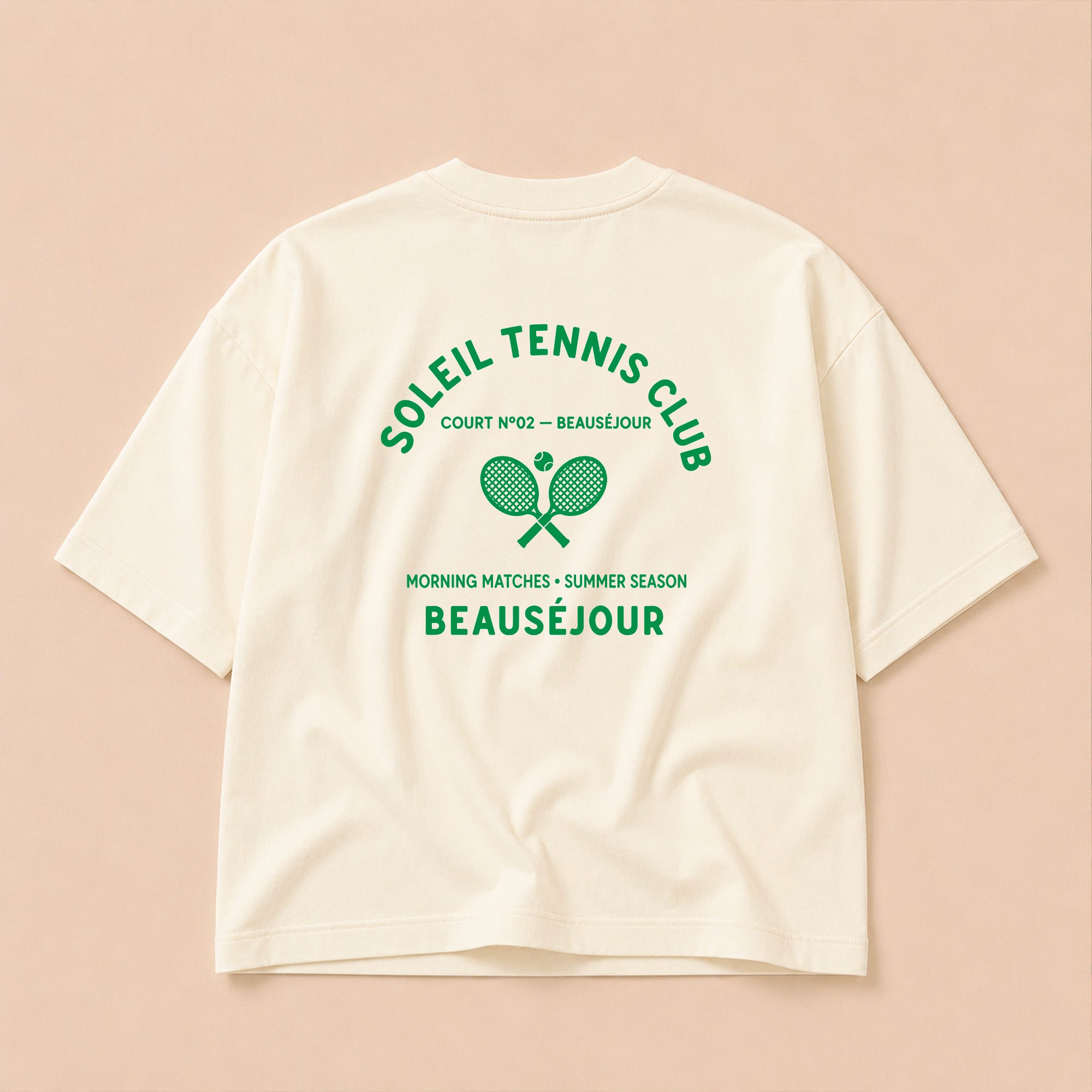 Packshot du t-shirt boxy crème Tennis Club Beauséjour, vue de dos, grand imprimé raquettes croisées et inscription Tennis Club.