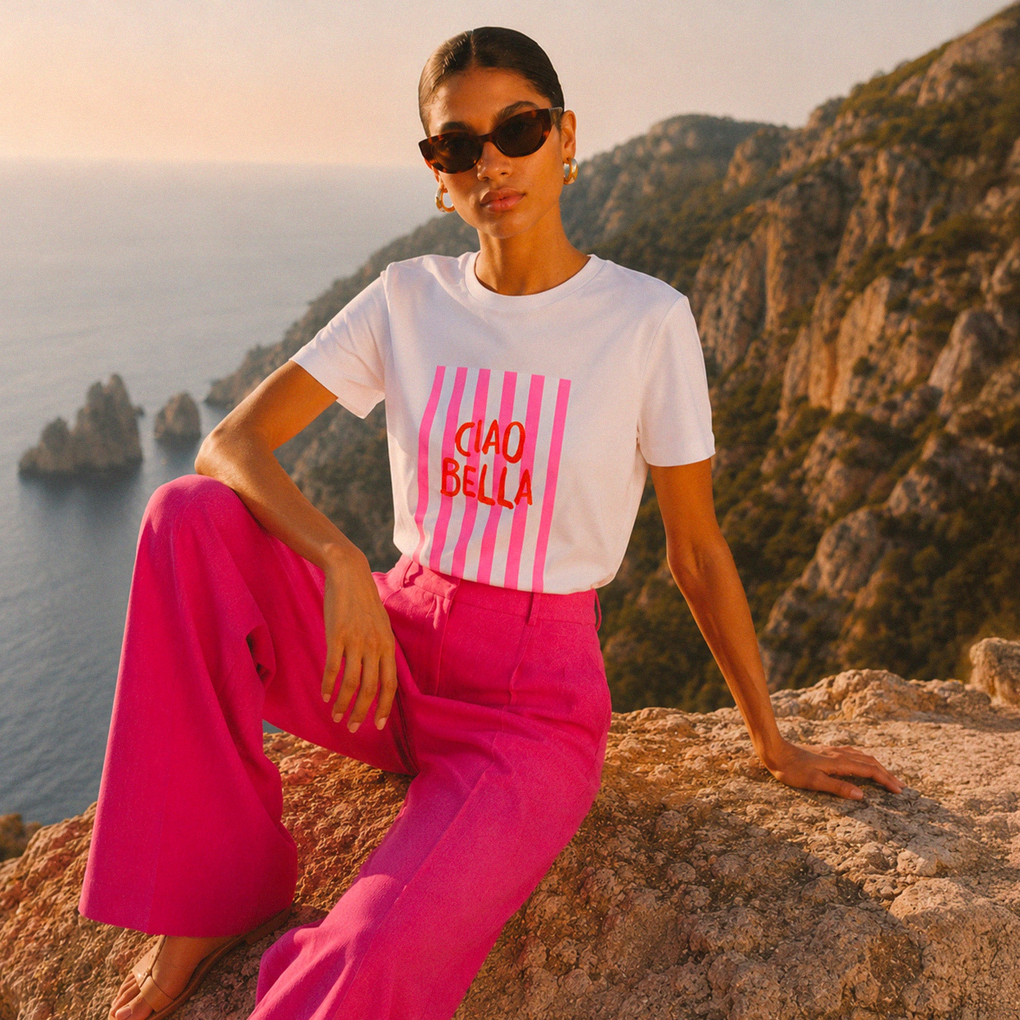 Femme portant un tshirt blanc Ciao Bella avec imprime rose au bord de la cote italienne