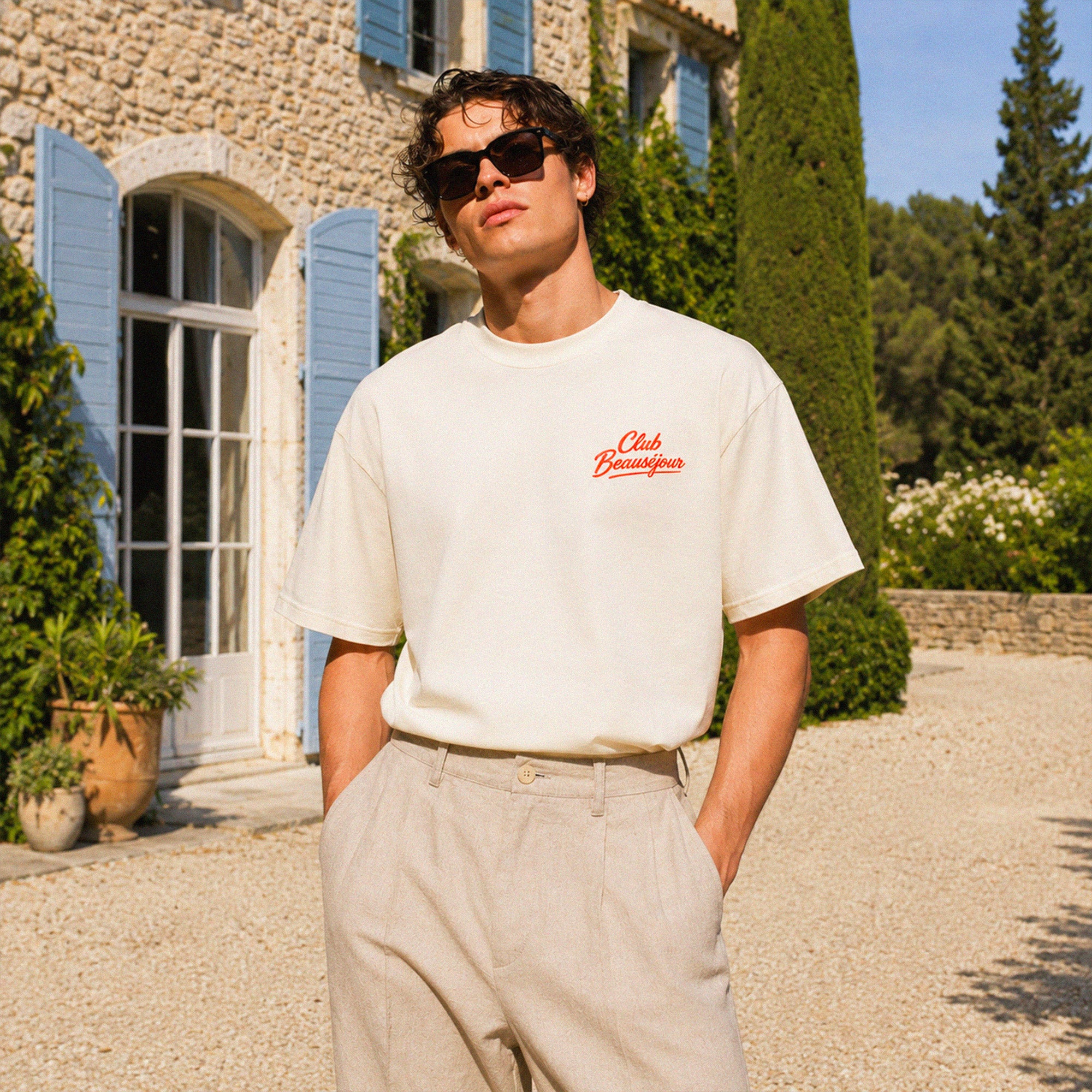 Homme portant le t-shirt oversize crème Club Beauséjour en coton premium 200 grammes avec coupe boxy estivale.